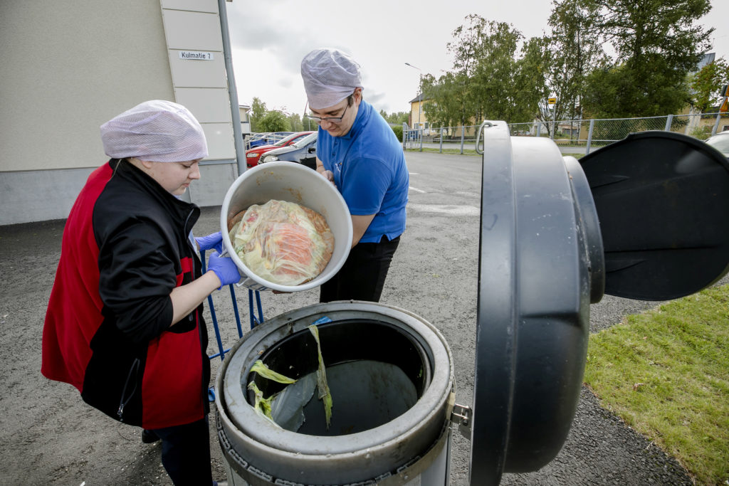 Mies ja nainen kippaamassa biojäteastiaa keräyslaariin.