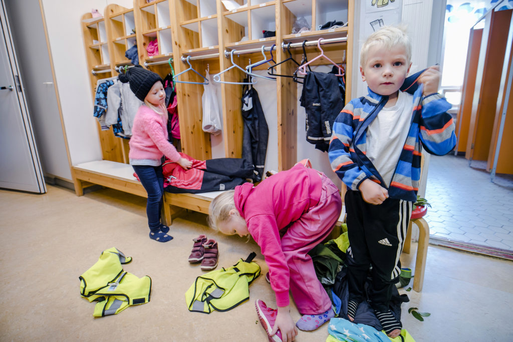 Lapsia päiväkodin eteisessä kuoriutumassa ulkovaatteista.