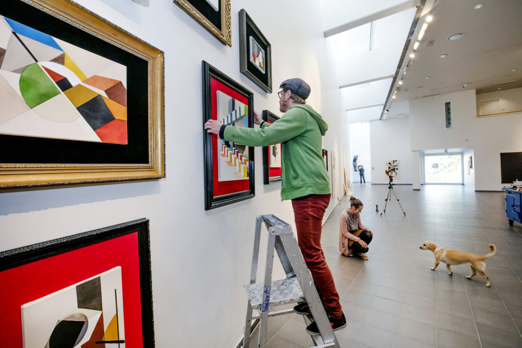 Artist putting up his painting on the art museum wall.