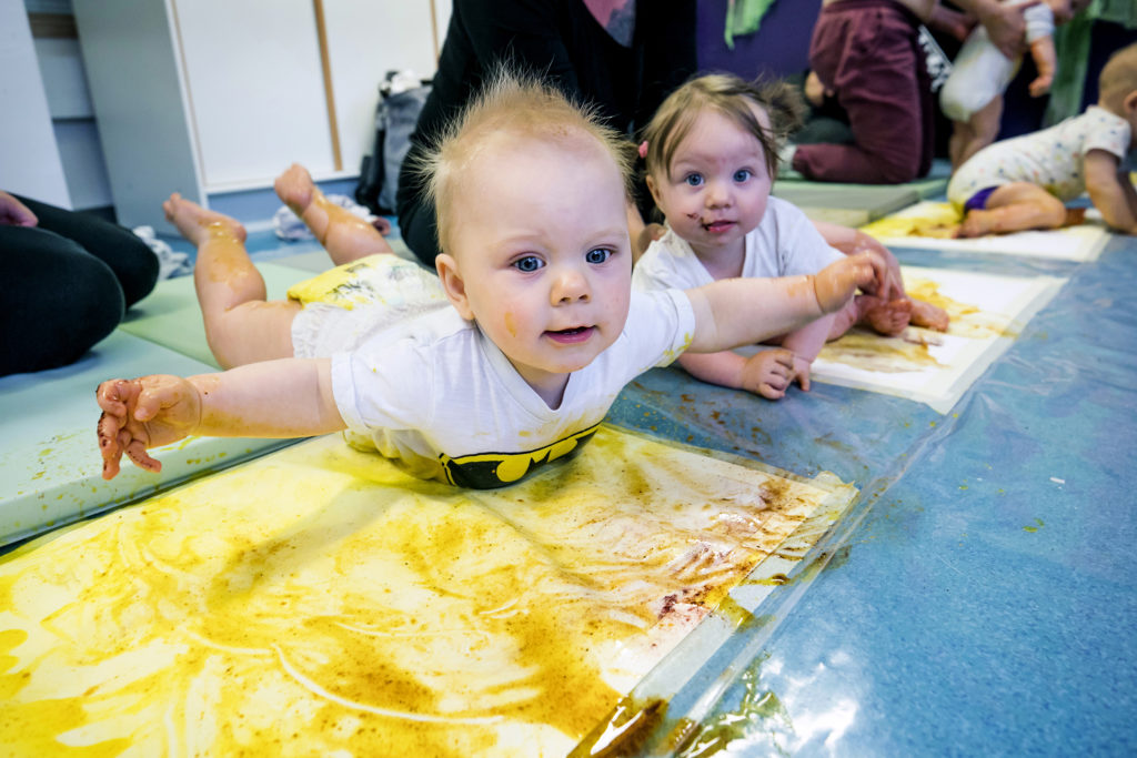 Bebisar som leker på golvet. Vauvoja värikylpyleikissä lattialla.