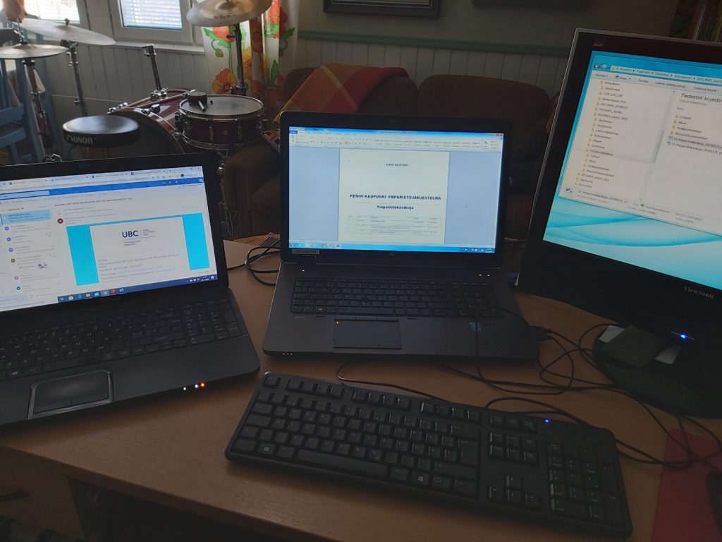 Kolme tietokonetta työpöydällä.