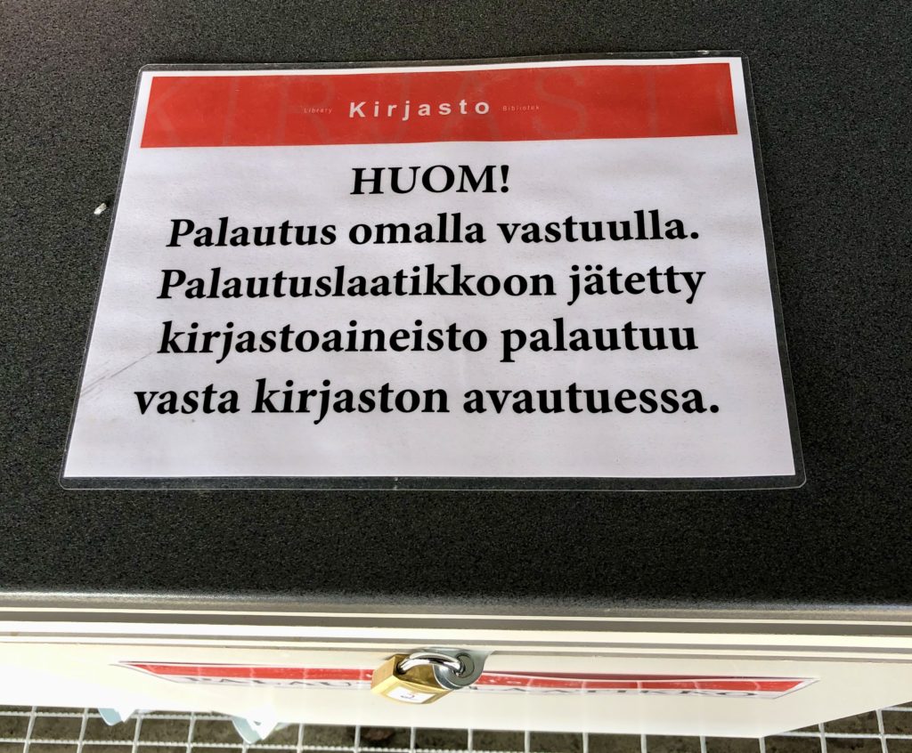 Kirjaston opaskyltti palautuslaatikoiden yhteydessä.