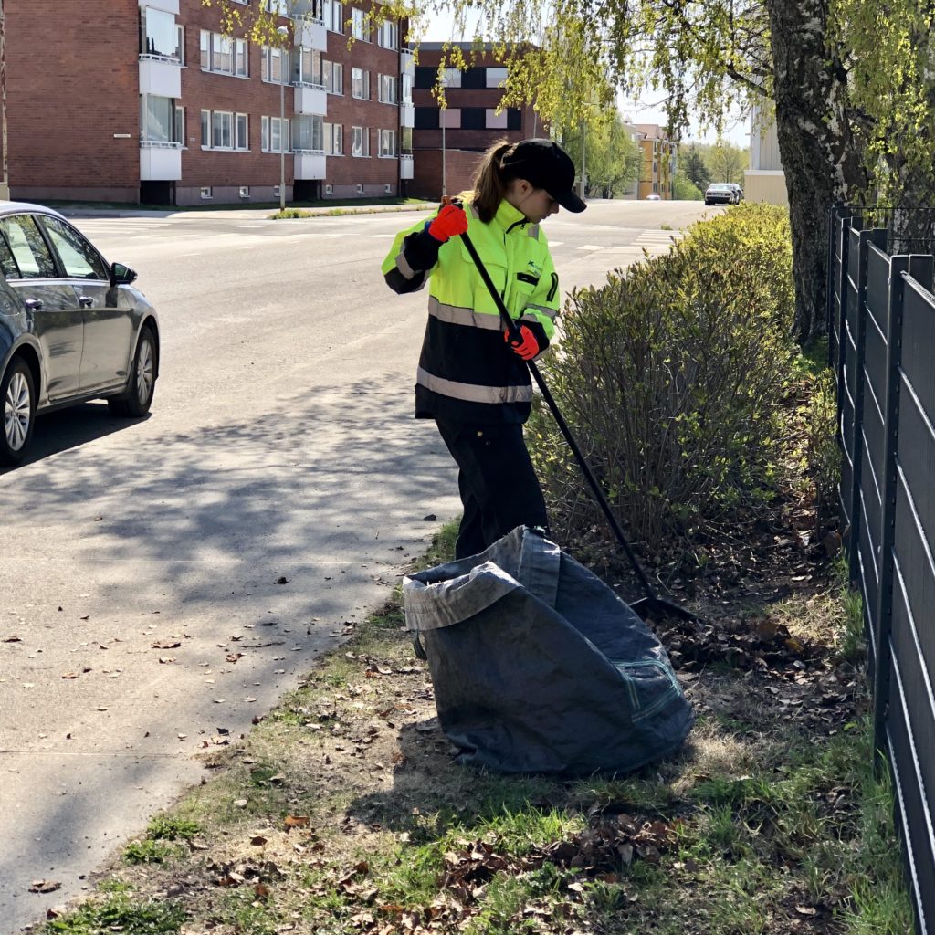 Kesätyöntekijä haravoi kadunvierustan nurmikkoa.