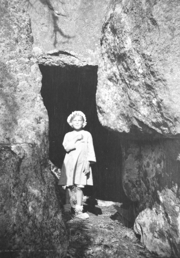 Pieni tyttö luolan suulla 1910-luvulla, mustavalkokuva.