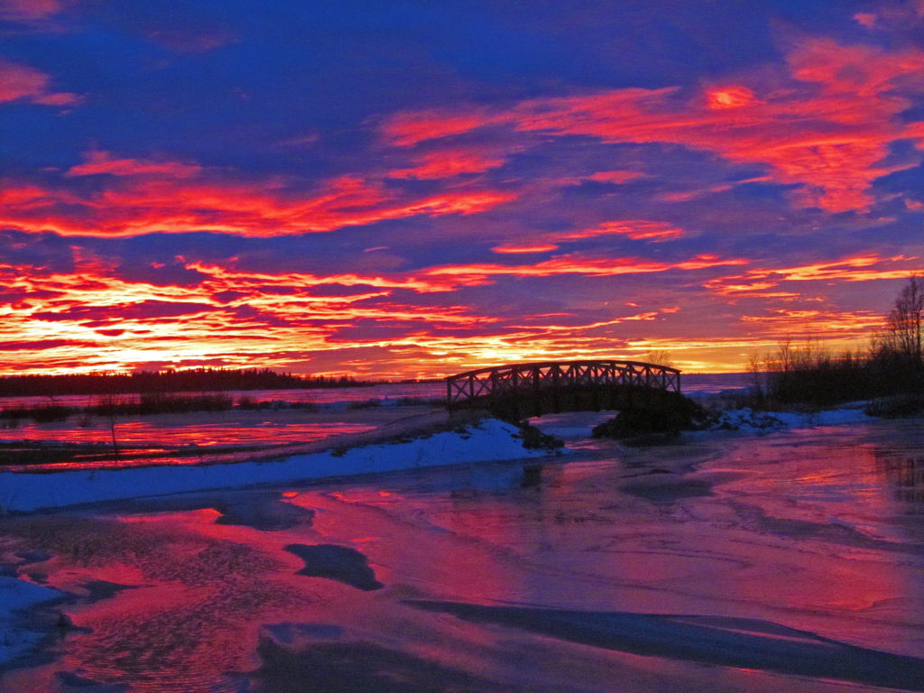 Puusilta merenlahdella, talvinen auringonlasku.