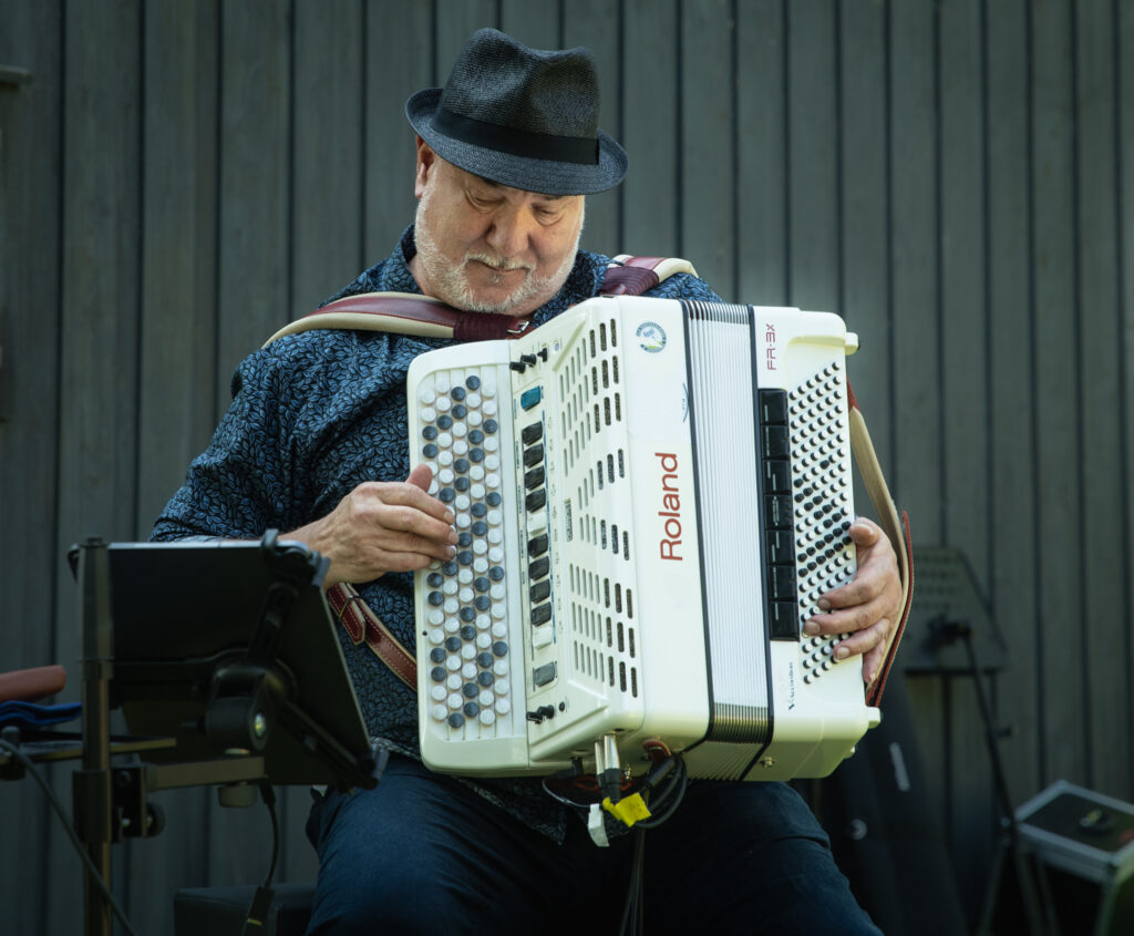 Hattupäinen mies soittaa kesittyneesti harmonikkaa. 